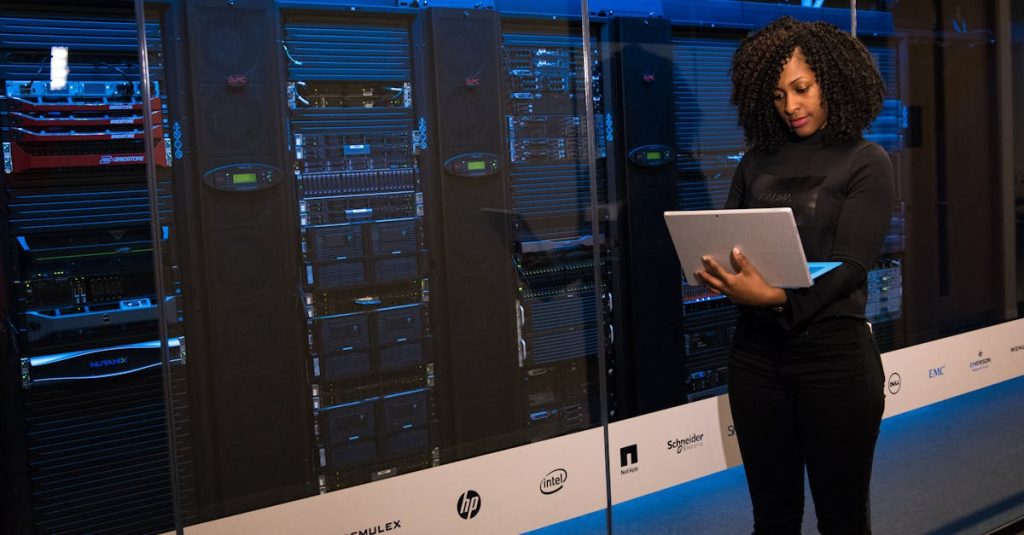 A female engineer using a laptop while monitoring data servers in a modern server room.