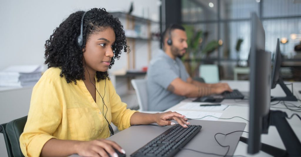 Two customer service agents working with headsets in a modern office setting.