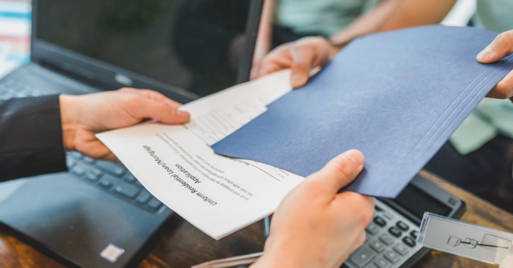 Close-up of hands exchanging real estate documents in an office setting.