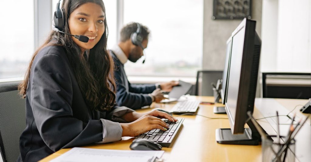 Smiling call center agents in an office providing customer support on computers.