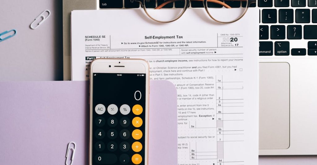 Flat lay of tax documents, smartphone calculator, and laptop for self-employment accounting.